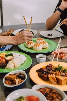 A vibrant spread of Asian dishes shared among friends, featuring dumplings and rice.