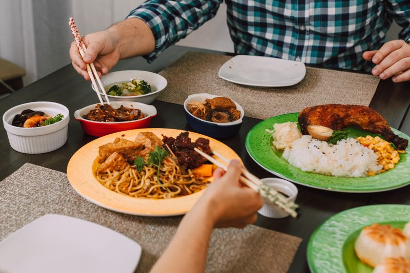 A delicious Asian meal featuring noodles, meats, and vegetables served with chopsticks on a dining table.