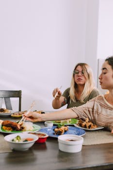 Two women enjoying a casual Asian meal at an indoor dining table, creating a relaxed atmosphere.