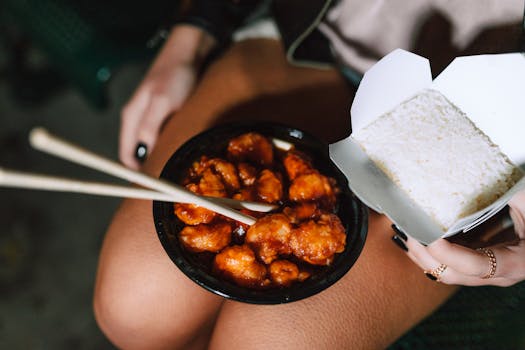 A delicious Asian meal featuring rice and savory chicken served with chopsticks.