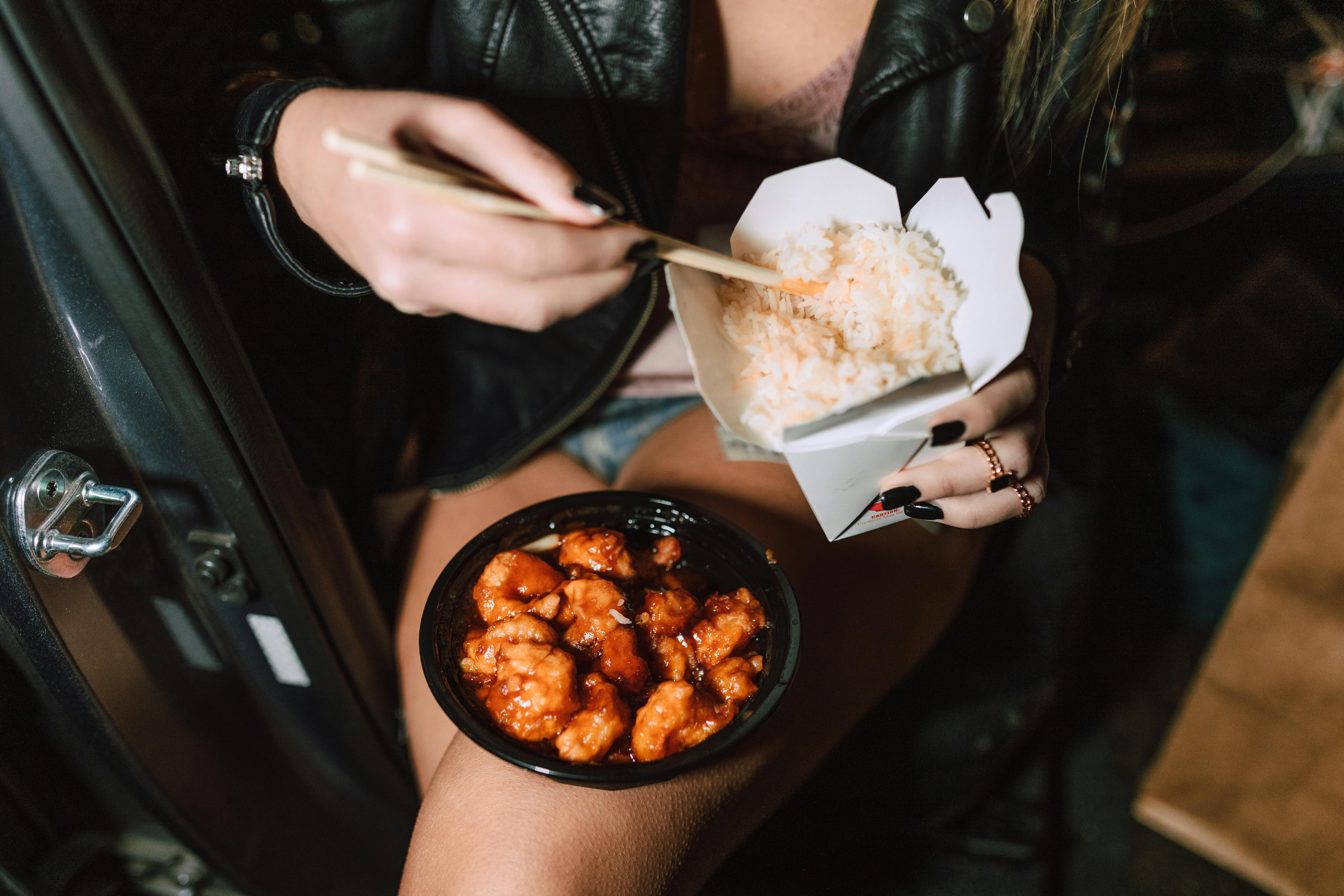 unrecognizable woman eating delicious takeaway asian dishes