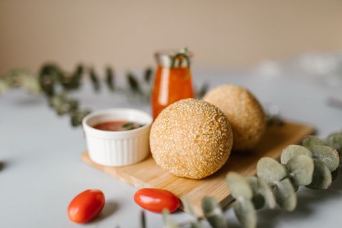 Free Close-up of sesame balls on a wooden board with tomato dip and decorations. Stock Photo