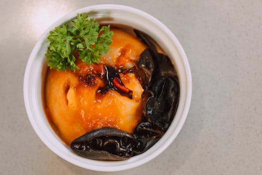Delicious egg custard topped with black fungus and parsley, served in a white ceramic bowl.