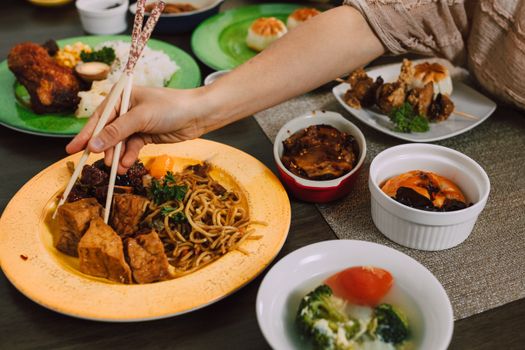 A vibrant display of Asian dishes with a hand using chopsticks, capturing the essence of tasty cuisine.