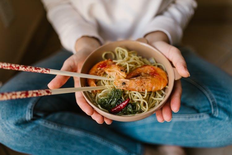 Person Holding A Bowl Of Noodles With Shrimps