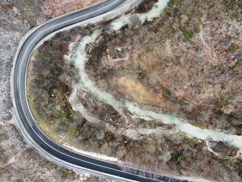 Aerial top view of empty curvy asphalt road running through rough heath in daylight