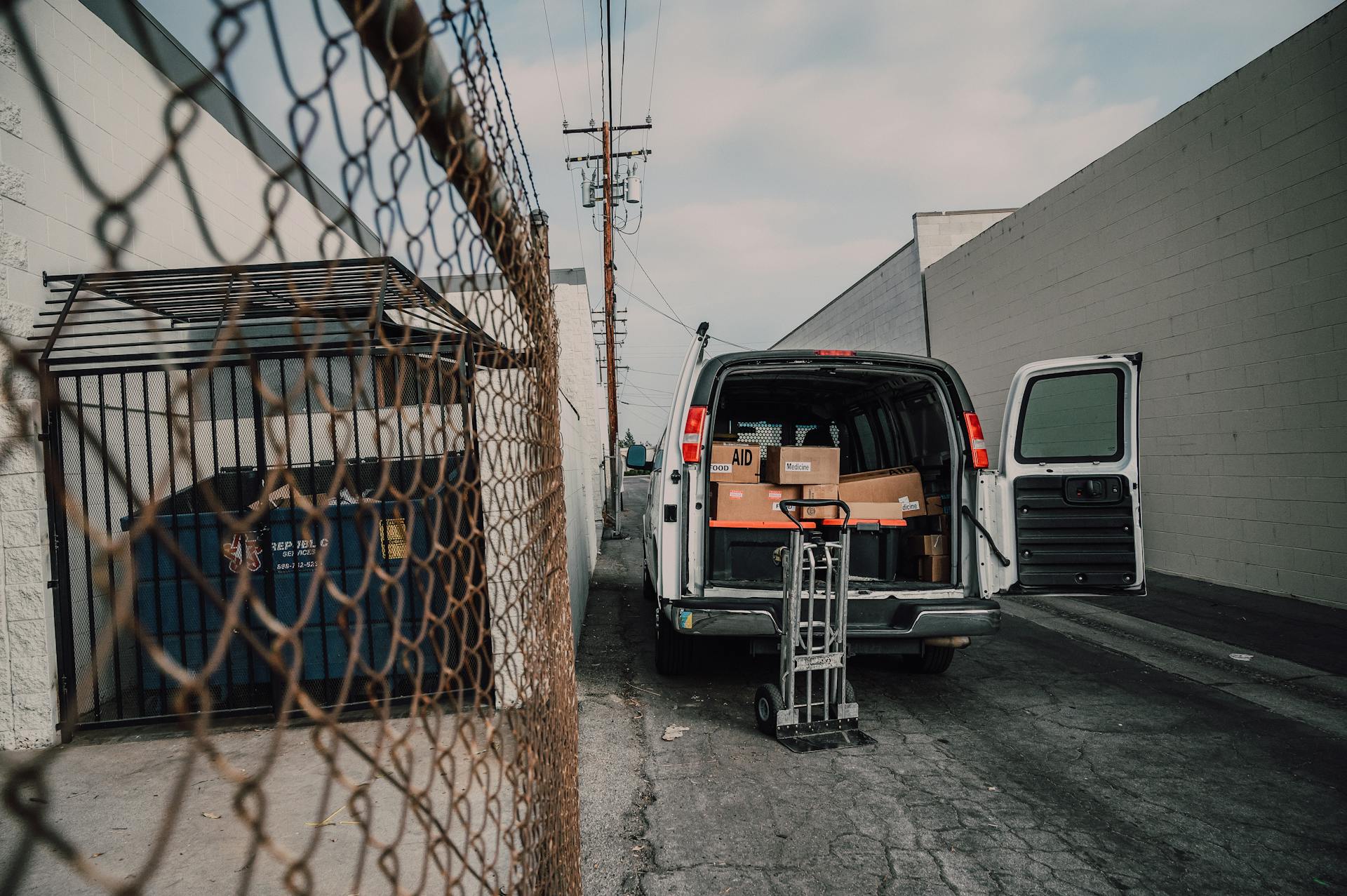 A Gray Push Trolley Beside a Van with Boxes of Donated Goods