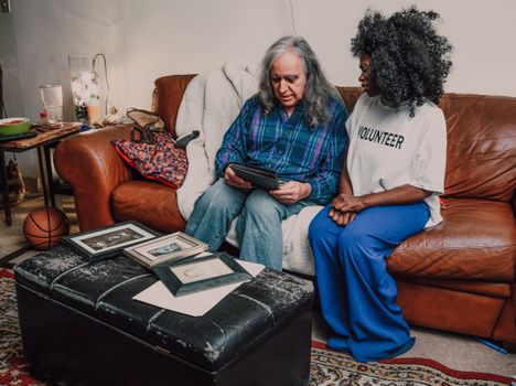 An emotional bonding scene between volunteers on a cozy sofa with family photos.