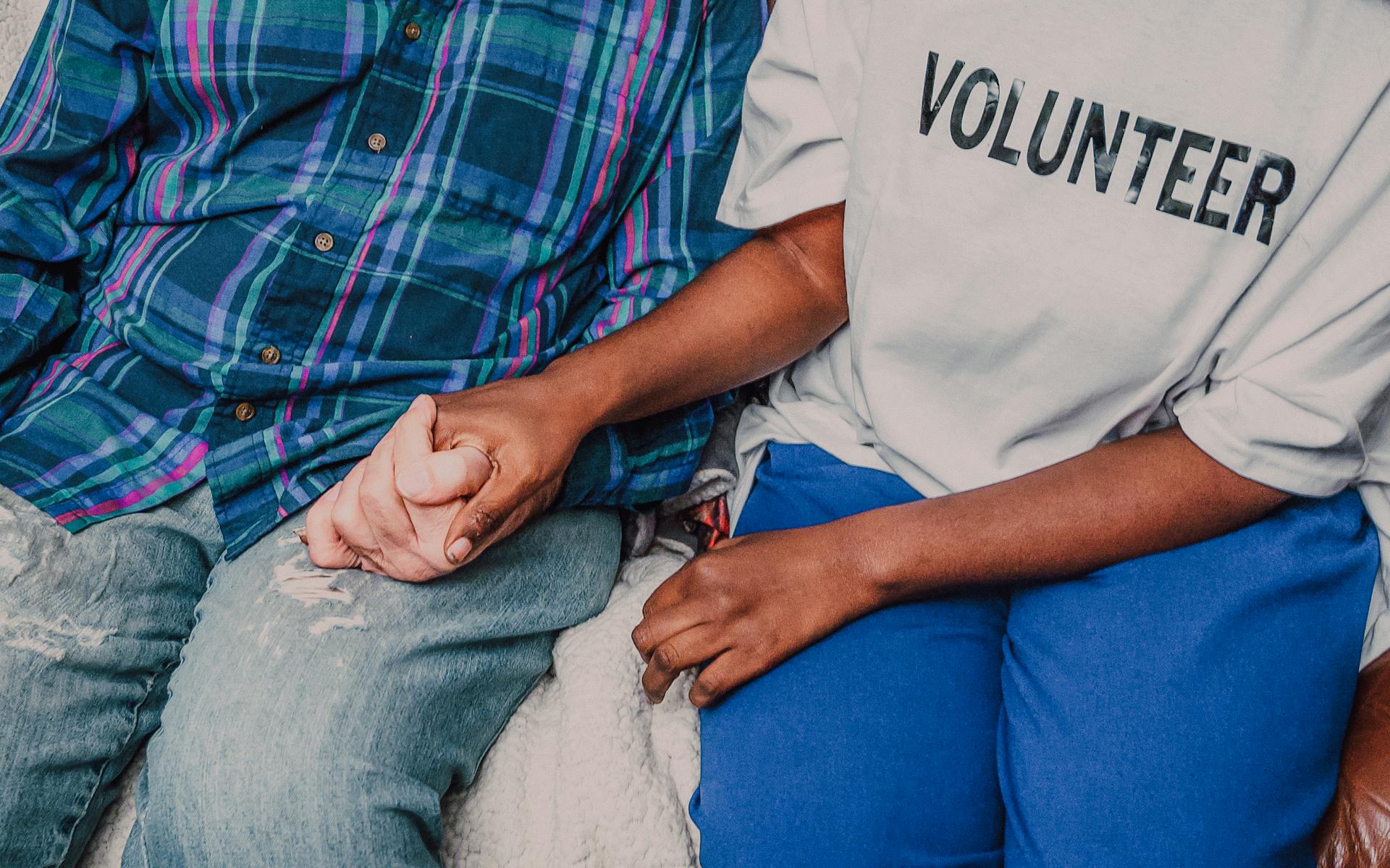 A volunteer holding hands with a senior, symbolizing care and community support.