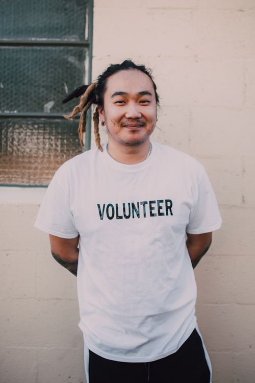 Free Portrait of a young male volunteer with dreadlocks standing outdoors, embodying community spirit and social good. Stock Photo
