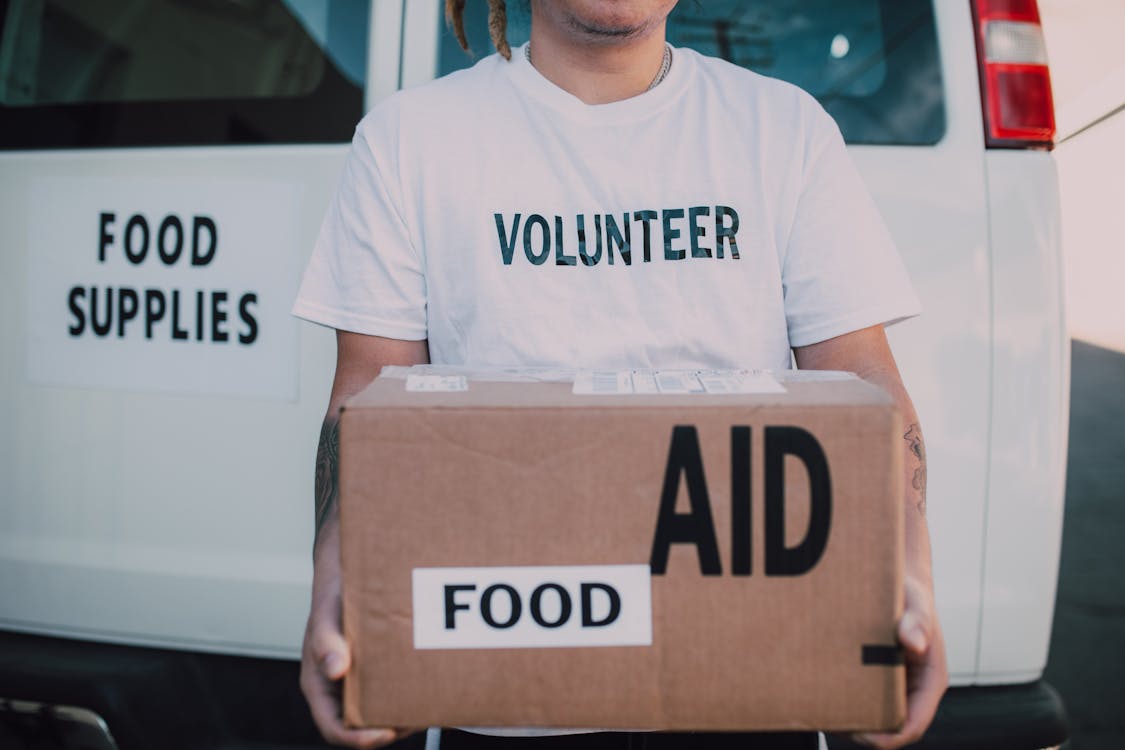Free Volunteer Holding Box of Food Aid Stock Photo