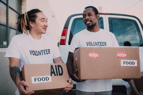 Free Men Volunteers Carrying Boxes  with Relief Goods Stock Photo