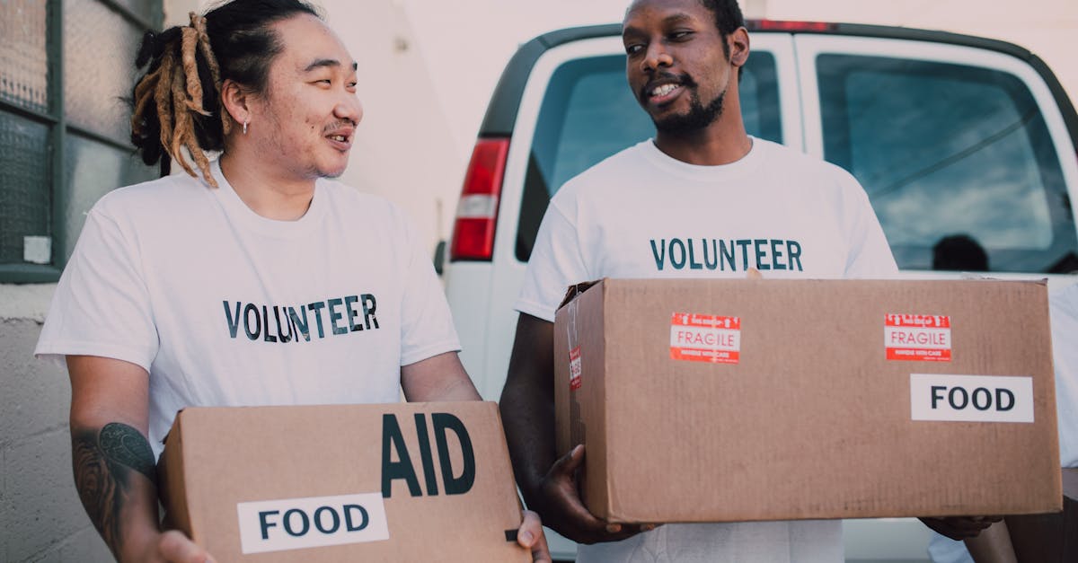 Photo by RDNE Stock project Two volunteers distributing food aid boxes for community relief outdoors.