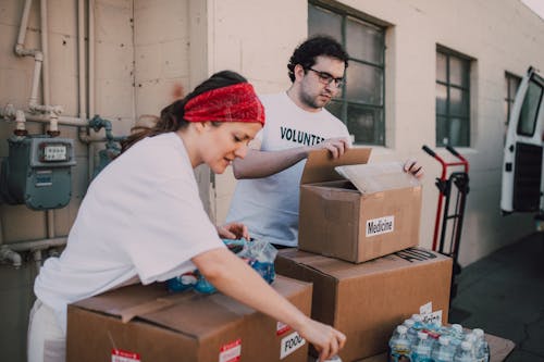 Free A Man and a Woman Packing Relief Goods in Boxes Stock Photo