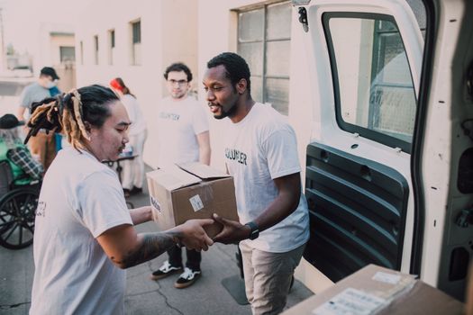 Volunteers working together to distribute donated supplies from a van.