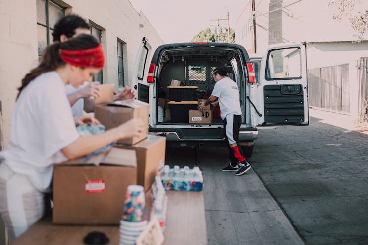 A Person Taking Out A Box Of Supplies In A Van