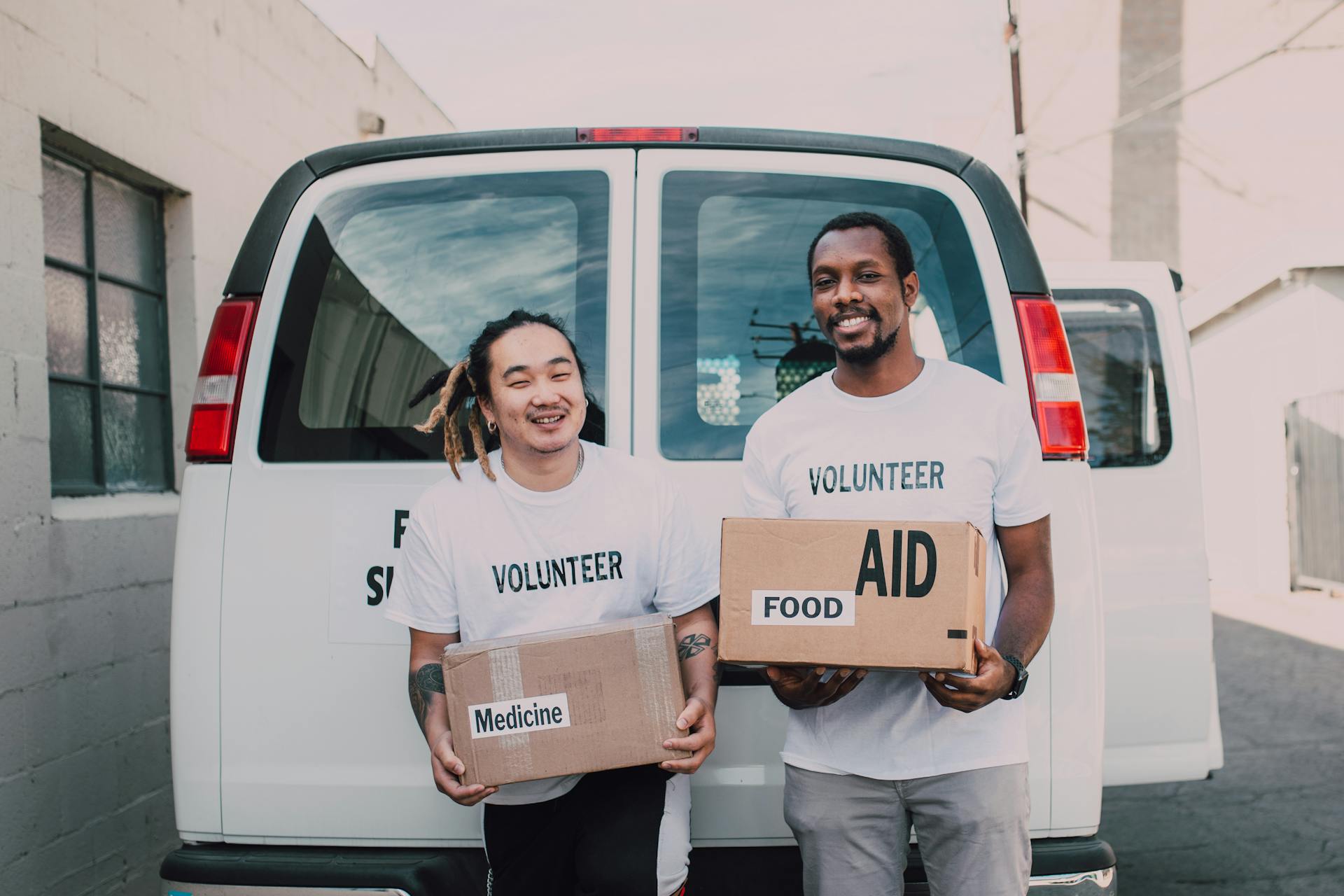 Volunteer Men Holding Medicine and Food Relief Supplies