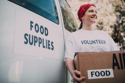 A Woman Standing Beside the White Van Carrying a Brown Box