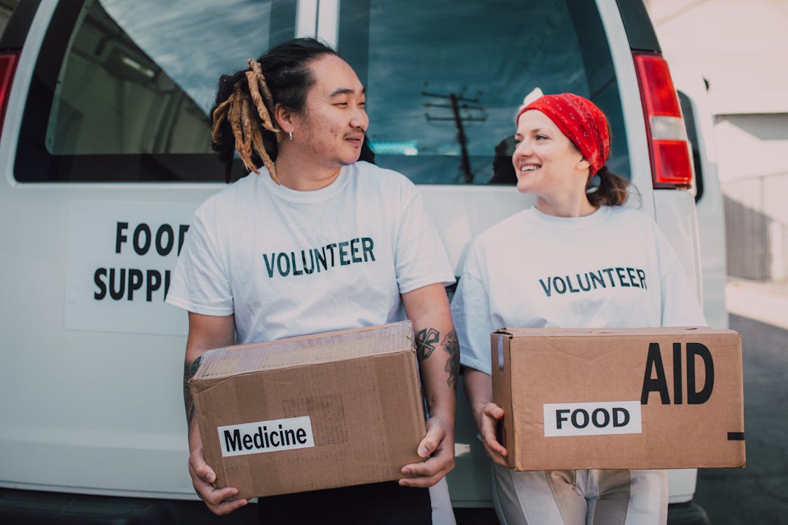 Free A Man and Woman Carrying Medicine and Food Cardboard Boxes Stock Photo