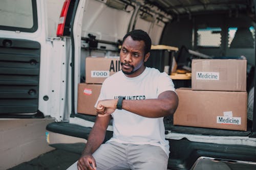 A Man Sitting on the Van Checking the Time on His Watch