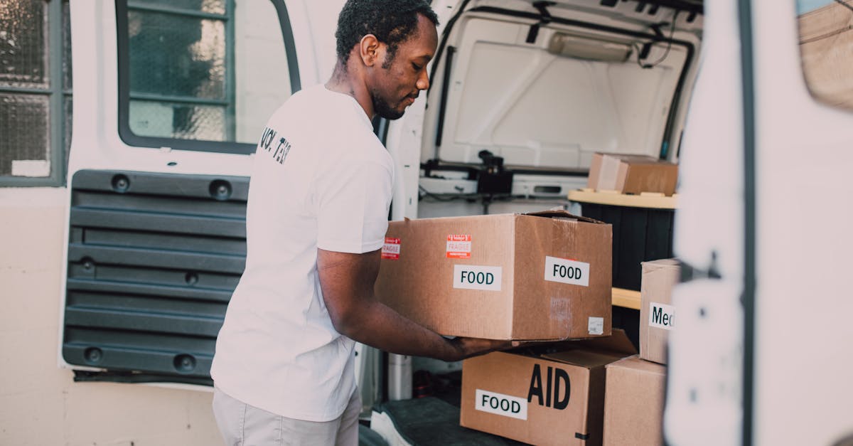 Man Placing Food Labelled Carboard Boxes Inside The Trunk of a White Van