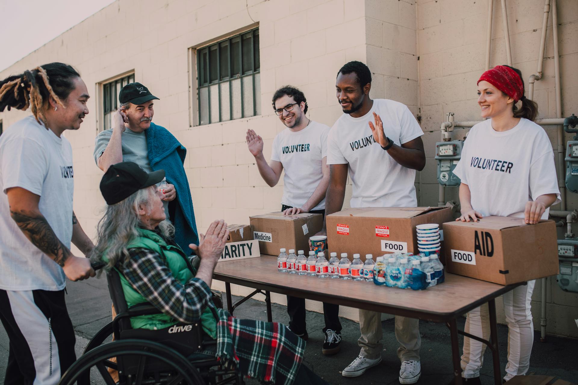 Volunteers Happily Assisting an Old Man on a Wheelchair For Charity