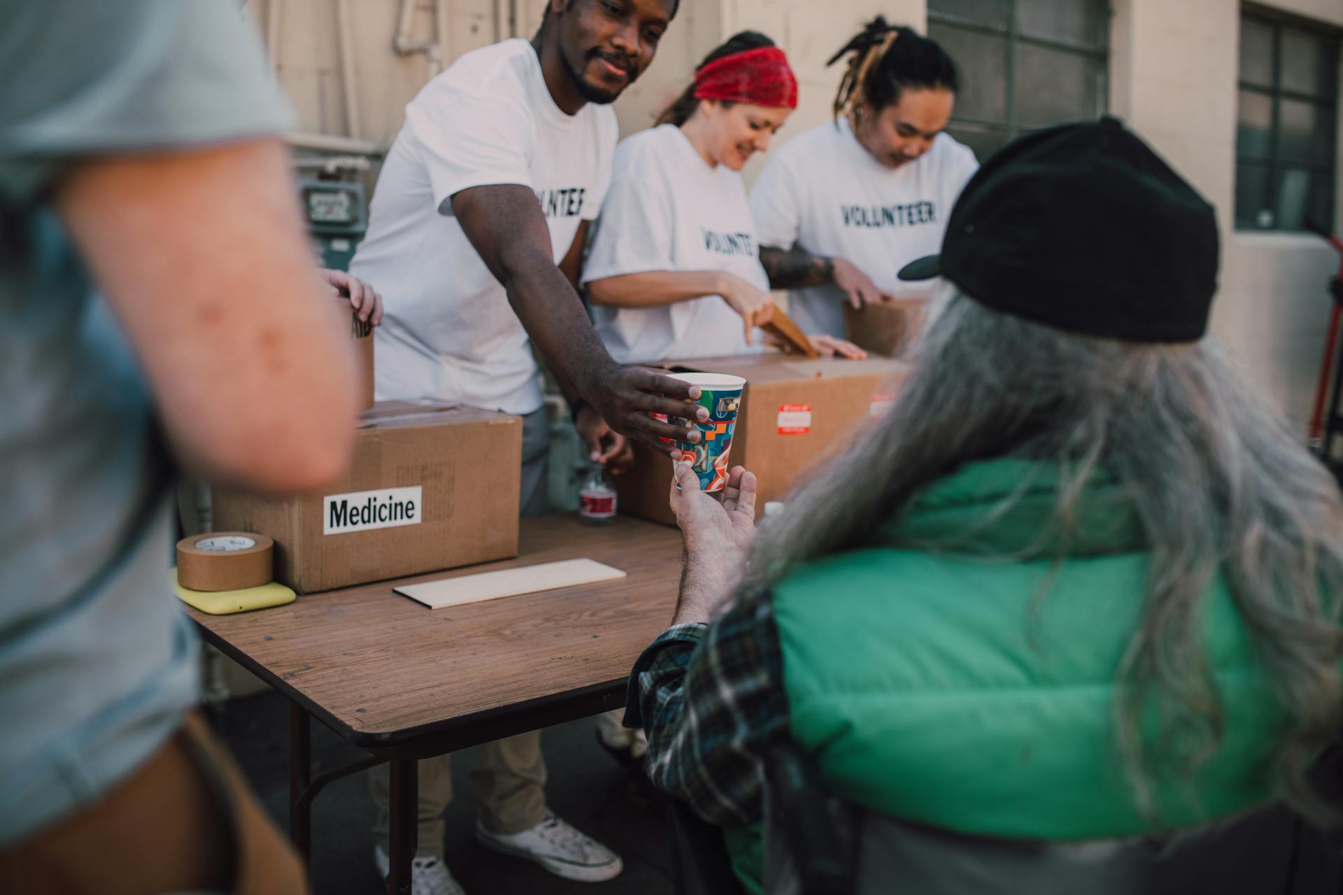 A Volunteer Giving a Cup to a Man