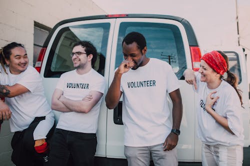 Adults in White Crew Neck T-shirt Standing Behind White Van