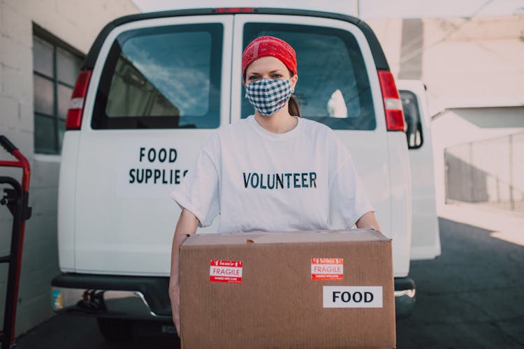 A Volunteer Wearing Face Mask Holding A Carton Box With Food Label