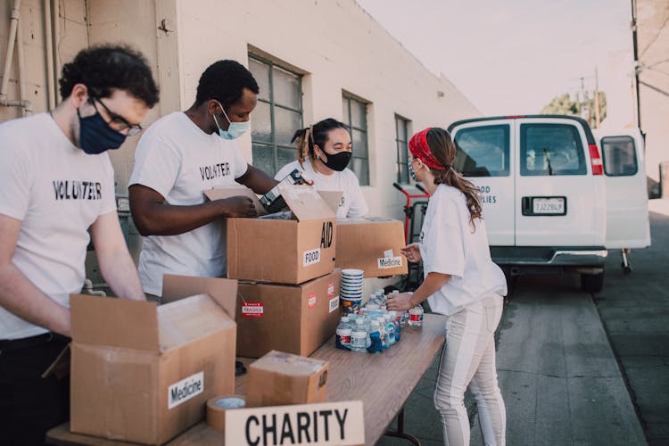 A Group Of Volunteers Taking Out Food Supplies From Cardboard Boxes