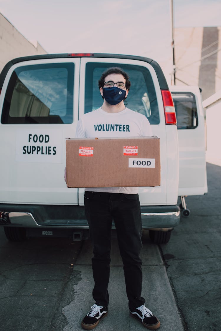 A Male Volunteer Carrying A Box