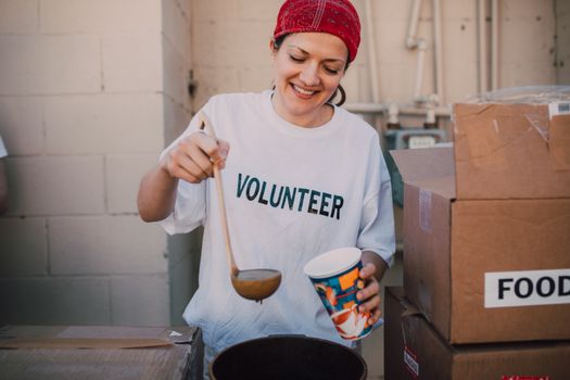 A cheerful volunteer serving food at a donation center, symbolizing generosity and community support.