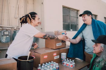 A Man in White Shirt Giving a Drink to an Elderly Man