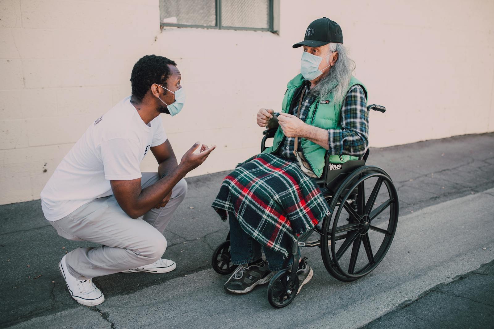 Support worker having a warm conversation with a man in a wheelchair outdoors