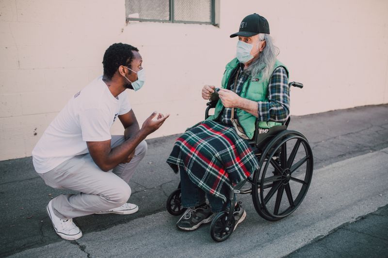 Caregiver helping elderly person with electric wheelchair rental
