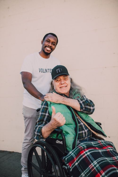 Free Happy volunteer with elderly man in wheelchair, showcasing kindness and community support. Stock Photo