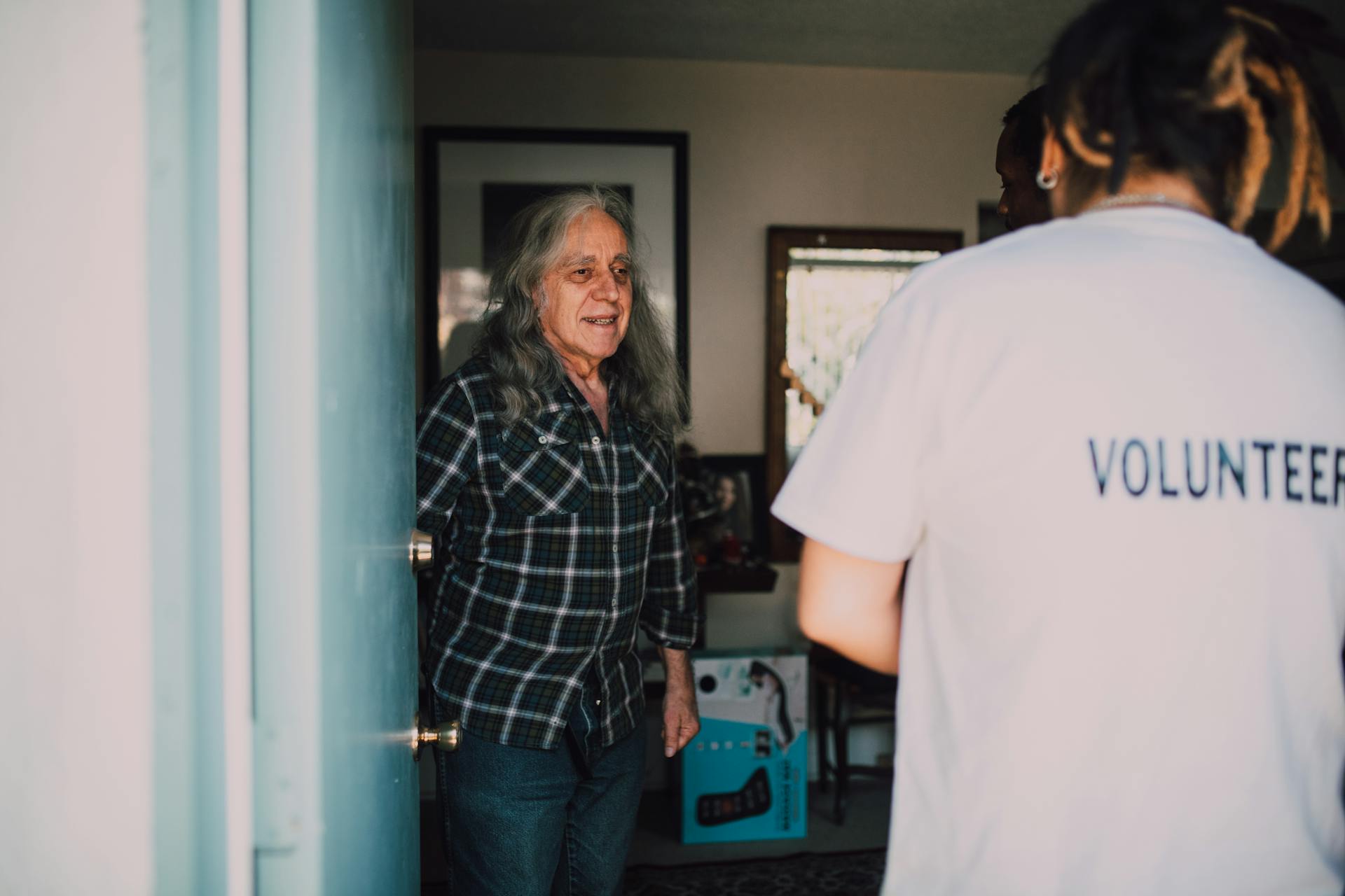 A volunteer visits an elderly person at home, creating a warm connection.