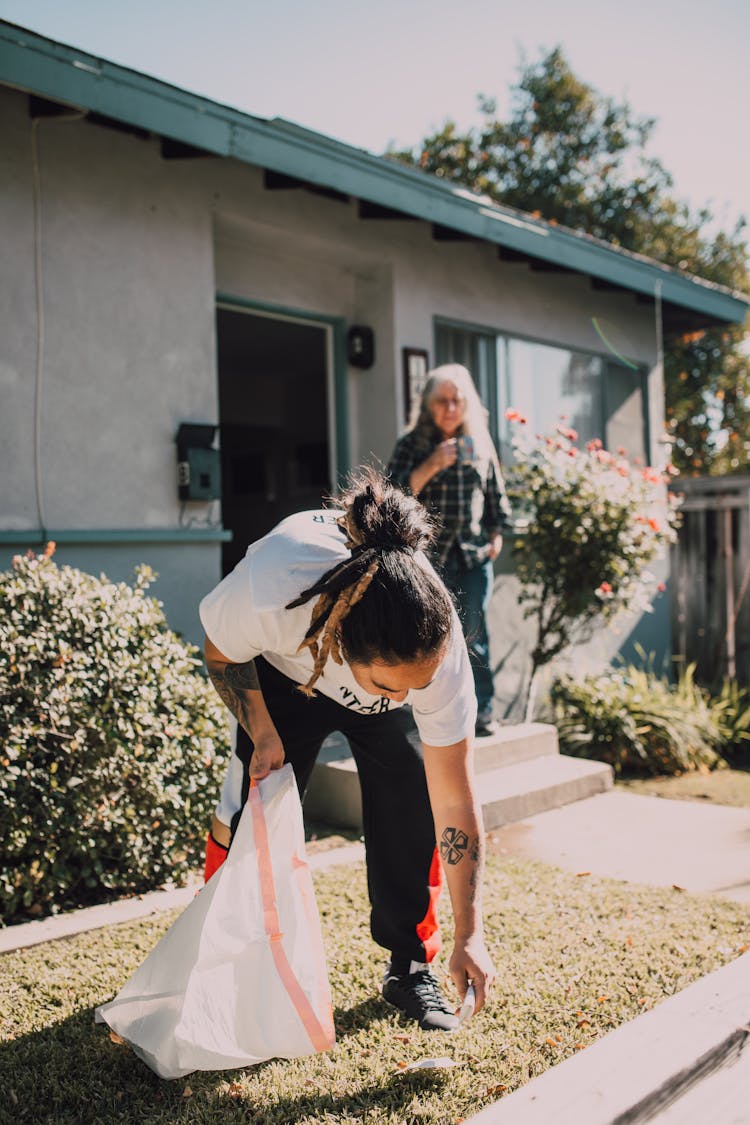 A Volunteer Cleaning And Elderly Man's Yard