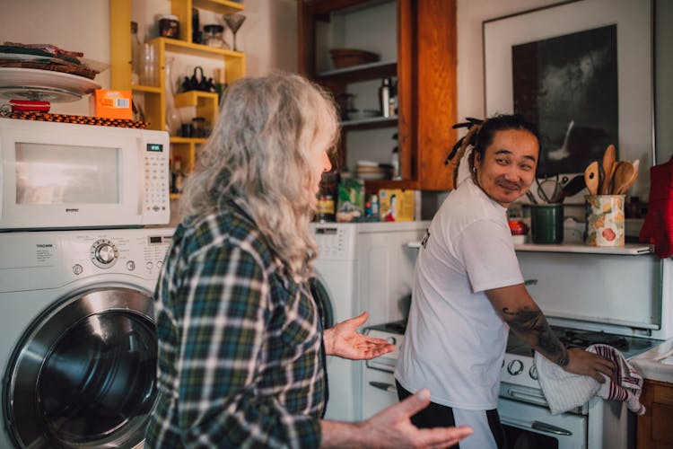 A Man Cleaning The Stove With Towel In The Kitchen