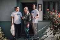 Two volunteers assist a community member outside their home, fostering social good.
