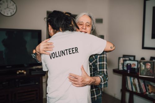 Free A volunteer embraces a senior woman in a heartfelt moment of support and love. Stock Photo