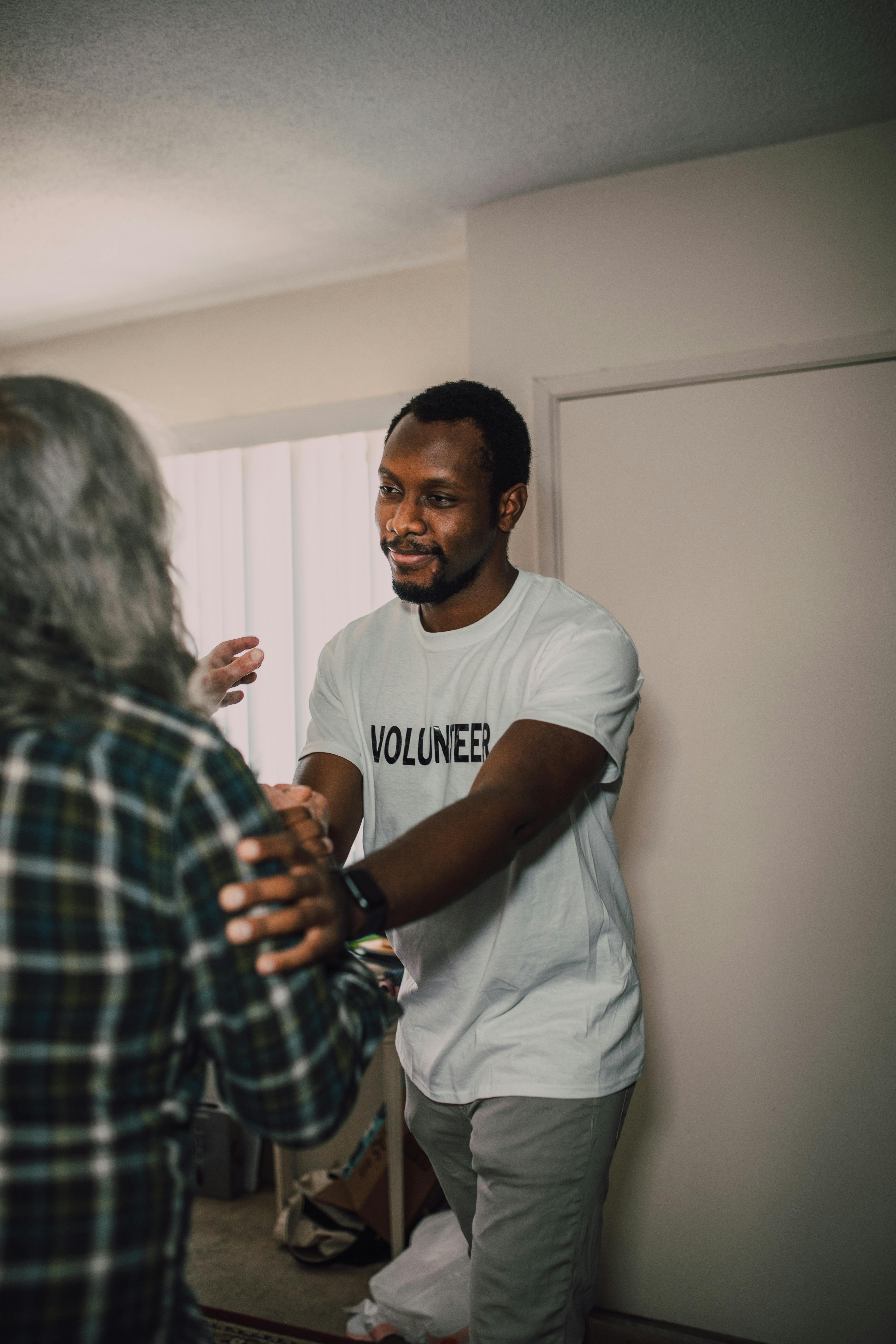 man in white t shirt assisting an elderly person