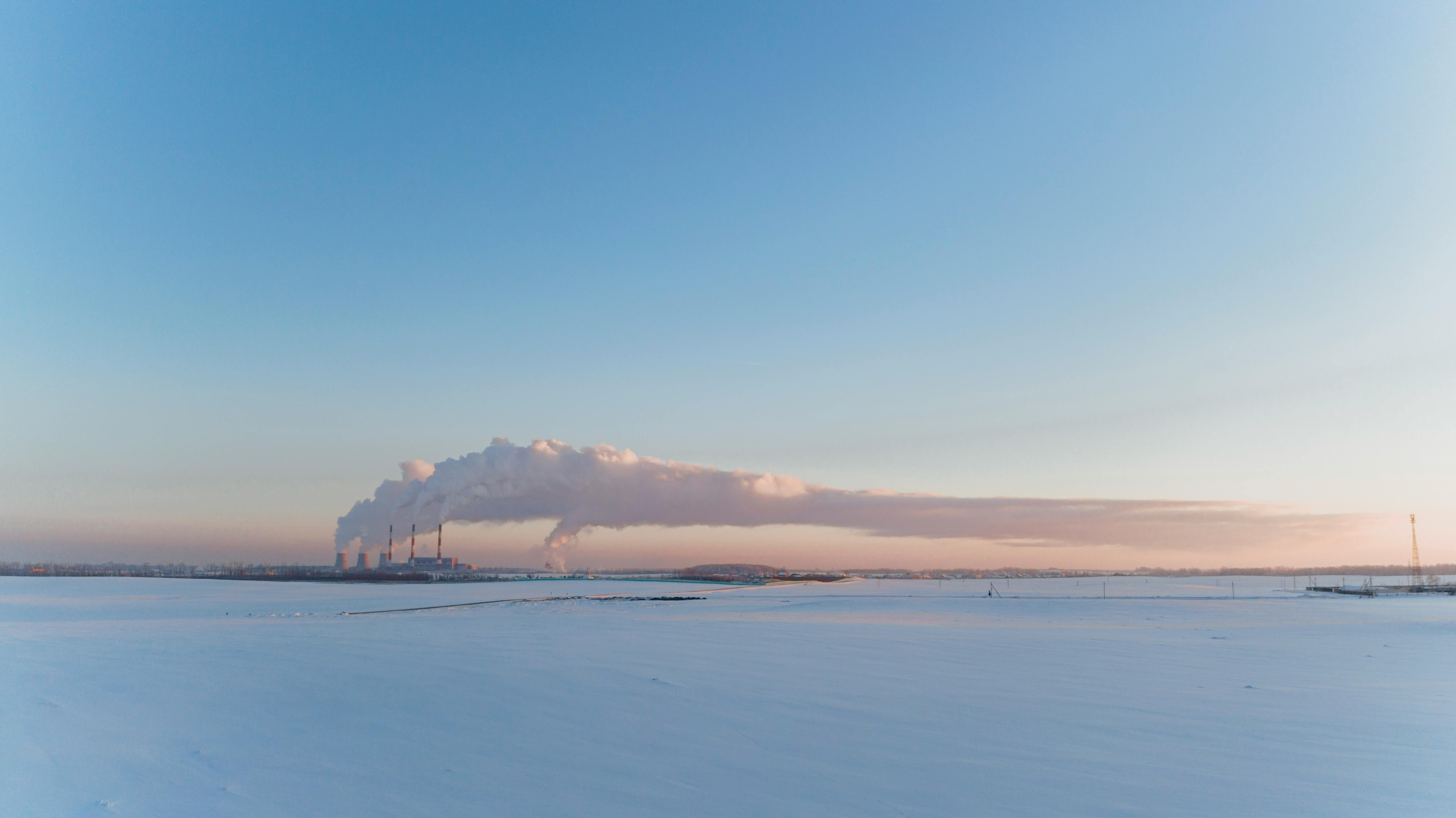 panoramic view of a flat terrain under snow with smoke from chimneys