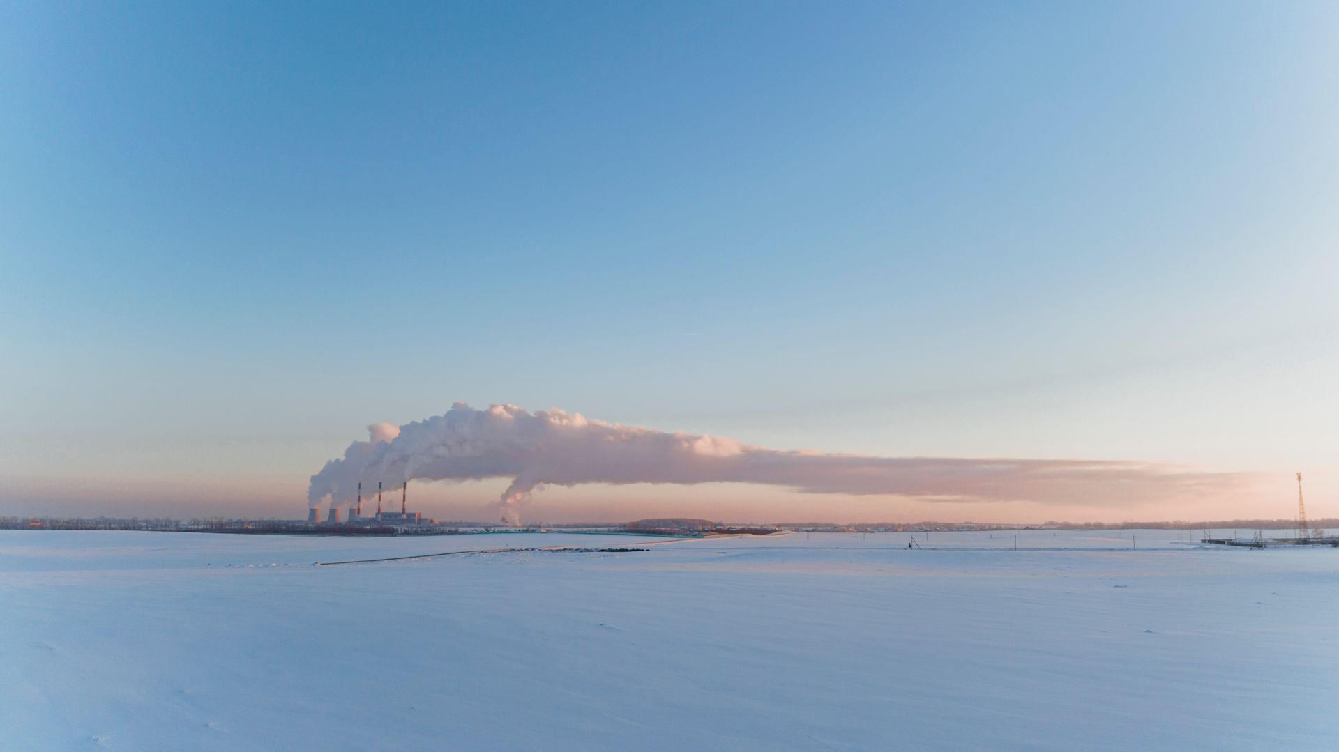 A cold winter scene of an industrial power station in Belarus with smoke rising under a clear blue sky.