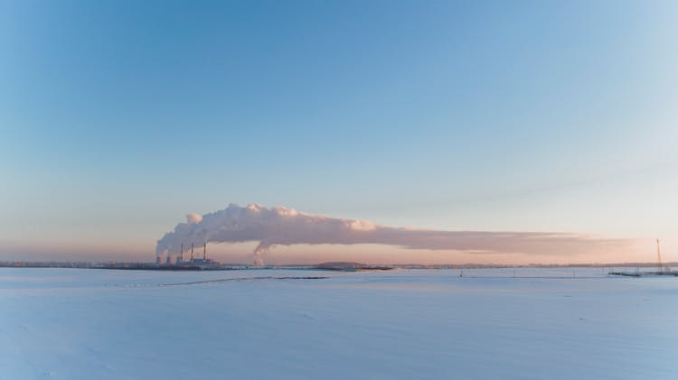 Panoramic View Of A Flat Terrain Under Snow With Smoke From Chimneys