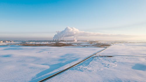 Panoramic View of a Flat Terrain under Snow with Smoke from Chimneys