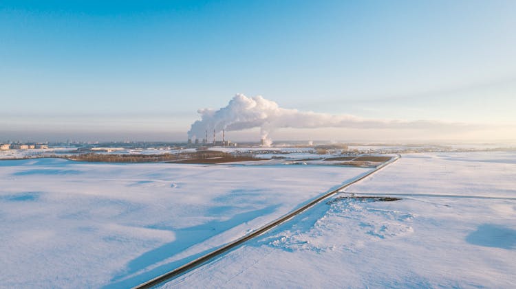 Panoramic View Of A Flat Terrain Under Snow With Smoke From Chimneys