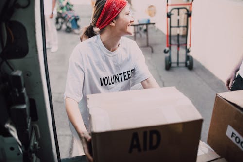 Woman in White Crew Neck T-shirt Loading a Box