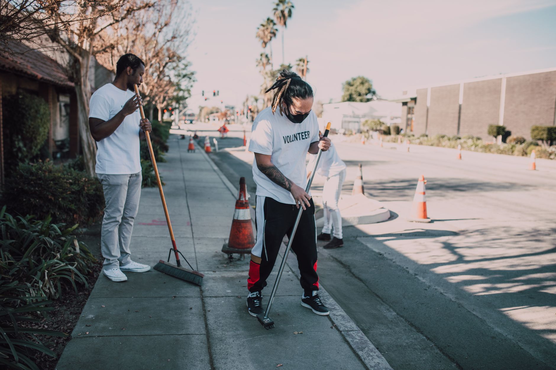 A group of volunteers cleaning a city sidewalk during the day, showcasing community spirit and teamwork.