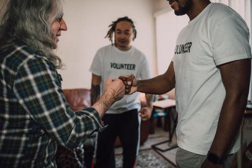 Free Three volunteers sharing a fist bump in a friendly indoor setting. Stock Photo